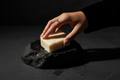 A hand lifting a wet ivory aloe soap bar from a black stone dish