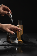 Skin Reset vegan skincare kit — cleanser, konjac sponge, hyaluronic serum and moisturizer on dark stone with model hands